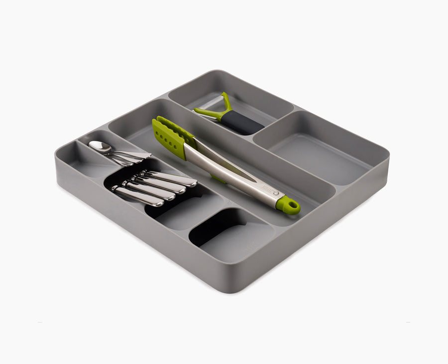 Joseph Joseph 85127. Gray silverware and utensil tray with example silverware, tongs, and peeler.